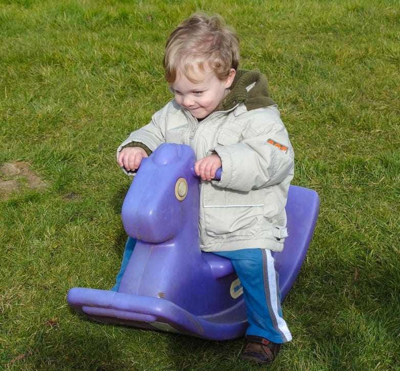 Photo of a baby outdoors on a rocking horse at Longscroft Nursery