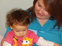 photo showing staff and child in Bumble Bees enjoying a book at Longscroft