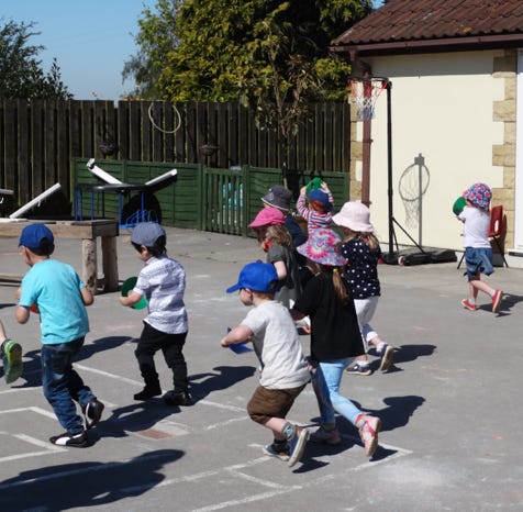Photo of children running together in playground at Longscroft Nursery
