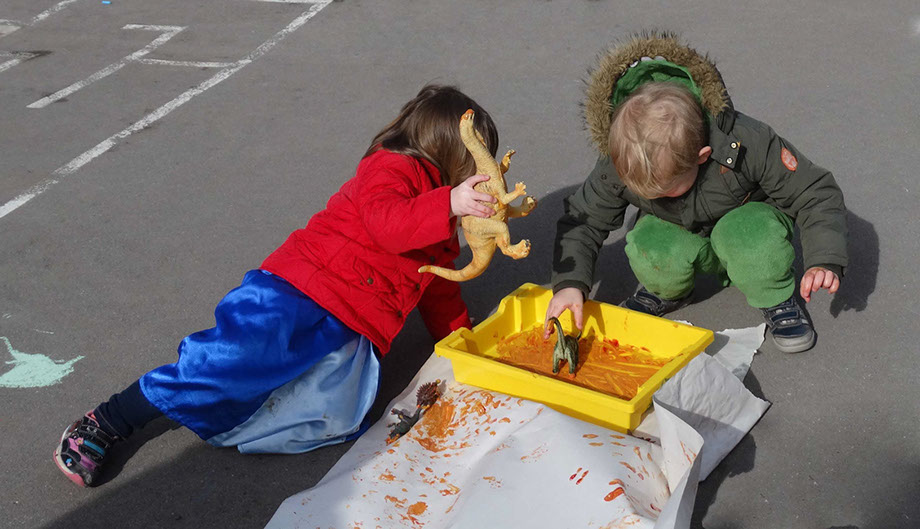 photo showing children outdoor painting with dinosaurs and paint at Longscroft