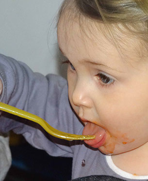 Photo of a girl self feeding lunch in Longscroft Dragonflies room