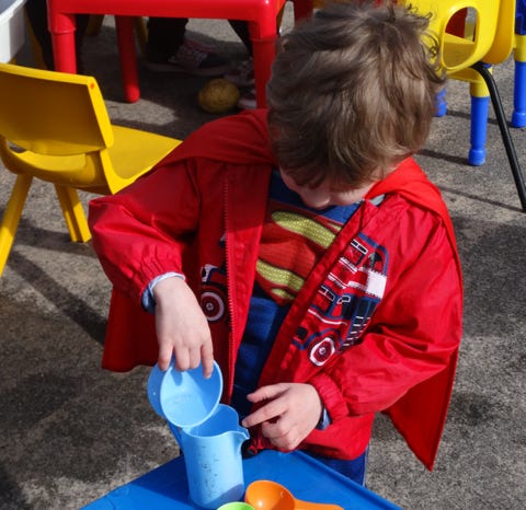 Photograph of a boy dressed as superman playing outdoors at Longscroft